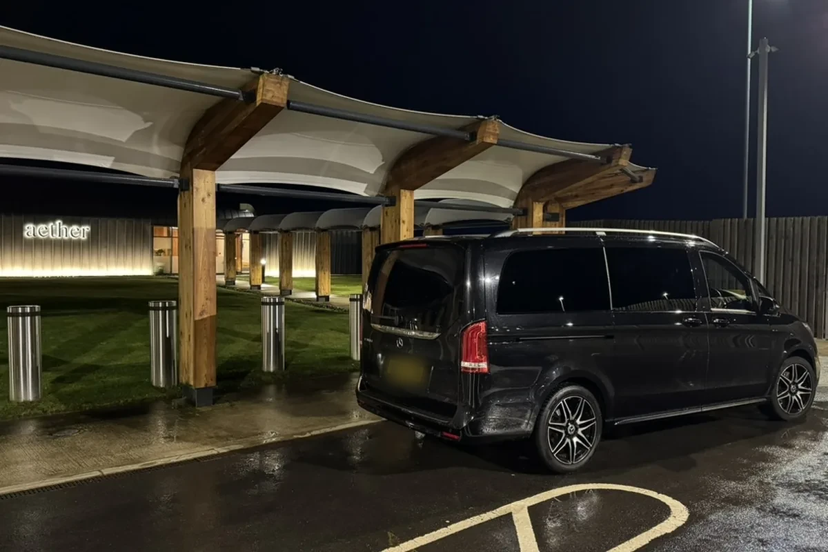 Black Mercedes-Benz V-Class waiting at the Aether private terminal near Manchester Airport at night