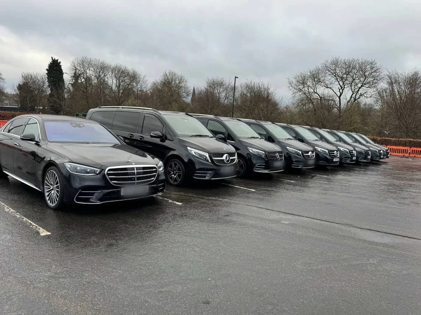 A row of black Mercedes-Benz S-Class and V-Class chauffeur cars lined up on a Manchester car park