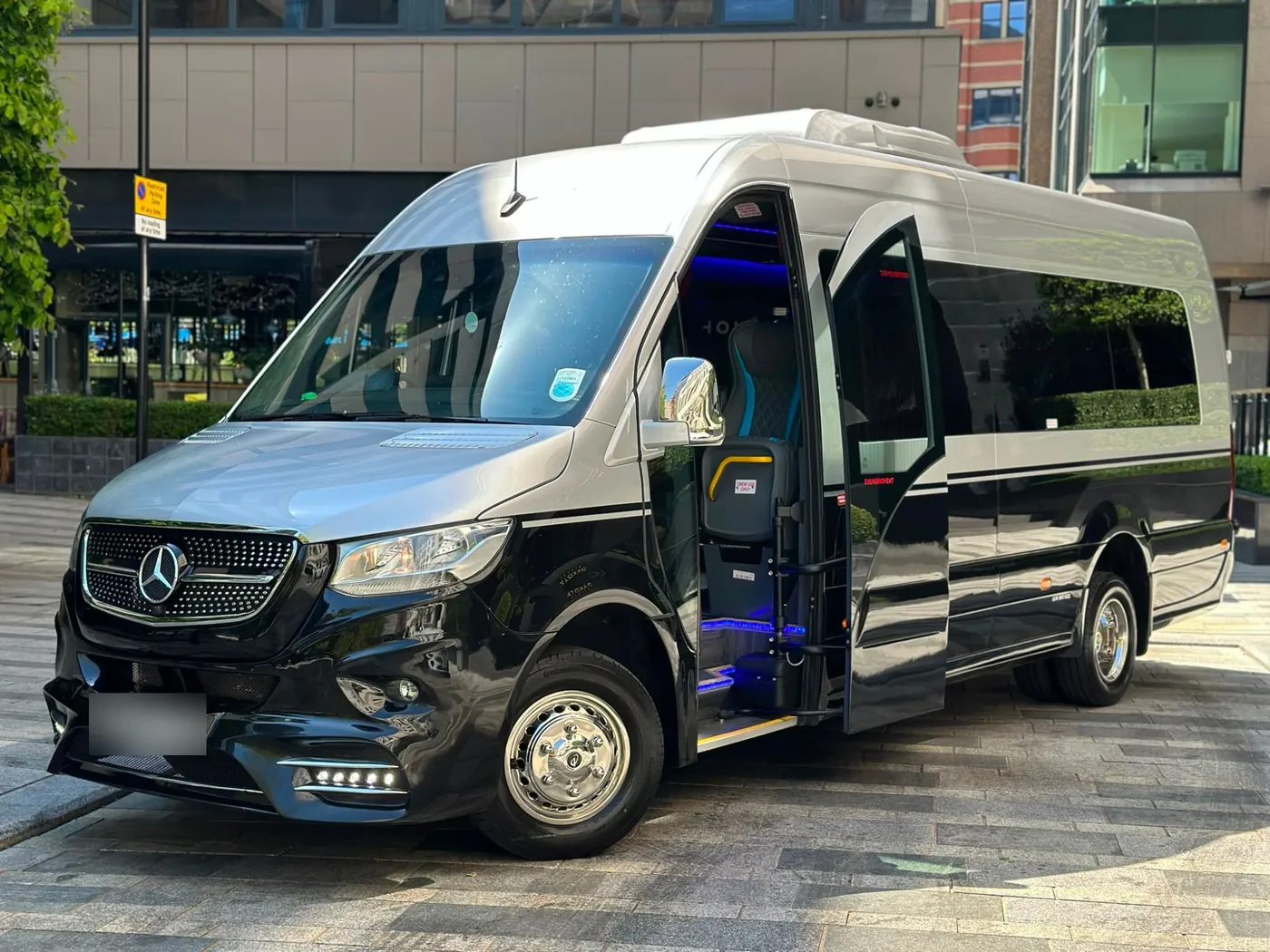 Silver and black Mercedes Sprinter 16-seater minibus with the passenger door open