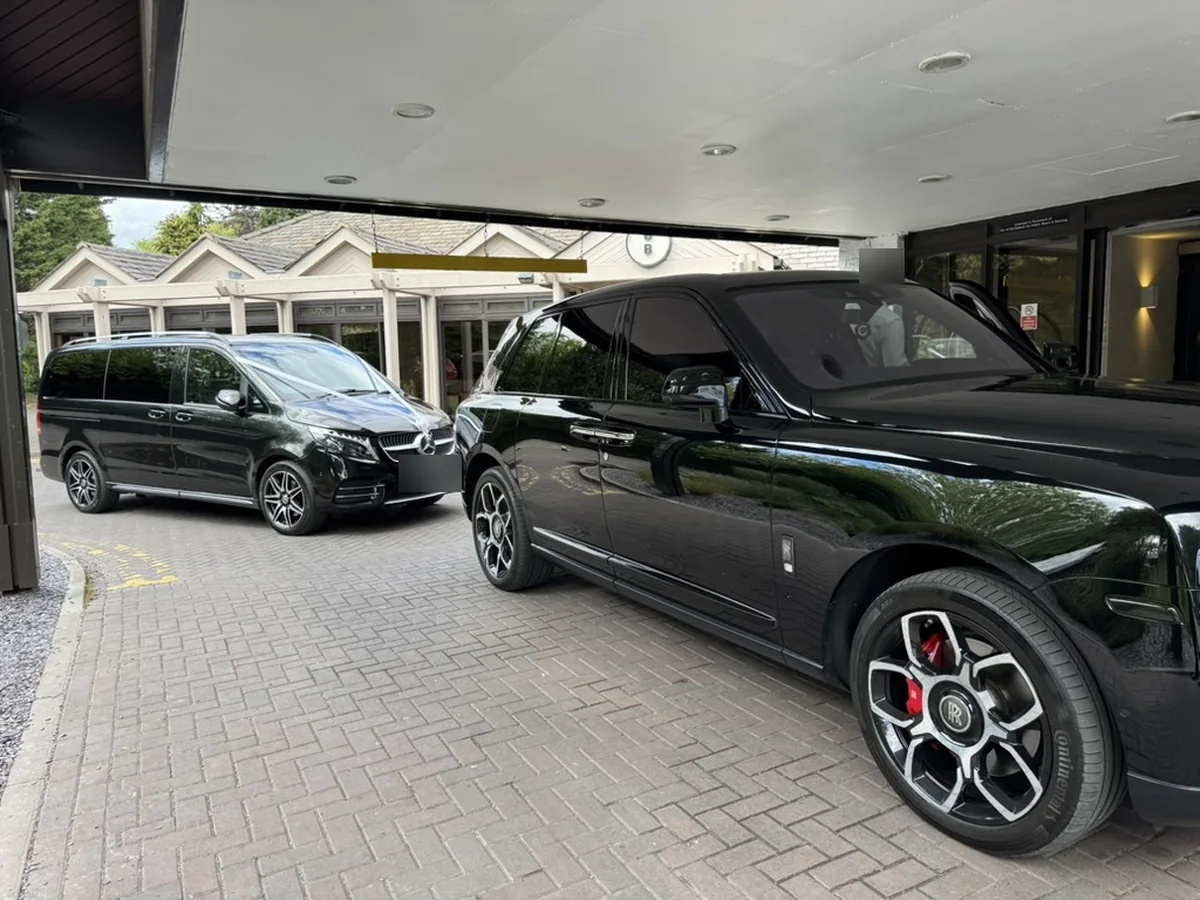 Black Mercedes-Benz V-Class beside a Rolls-Royce Cullinan at a hotel entrance, a pairing available through our partner network